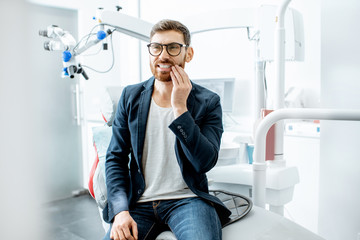 Businessman having a toothache waiting for the doctor in the dental office