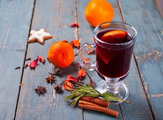 Wineglass with Christmas mulled red wine with spices and fruits on a wooden rustic table.