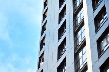 New block of modern apartments with balconies and blue sky in the background