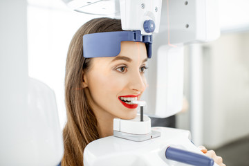 Young woman making panoramic shot of the jaw holding her face at the x-ray machine