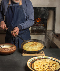 man holds pan with hot pancake. Holiday carnival