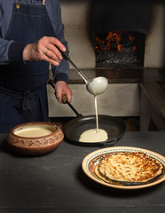 man holds a ladle and pours the dough into the pan