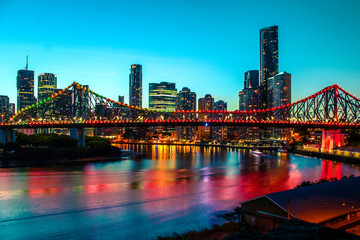 Fototapeta na wymiar Colourful skyline of Brisbane by night with illuminated Story Bridge and clear blue sky (Brisbane, Queensland, Australia)