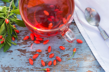 Fresh goji berries tea in a glass cup on a wooden table, healthcare and healthy eating concept