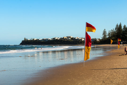 Typical Australian beach - Dicky Beach - at the Sunshine Coast in Queensland near Noosa Heads with flag, waves and white sand (Queensland, Australia)