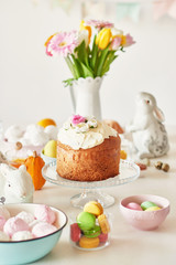 Obraz na płótnie Canvas Easter sweet bread, Easter cake and multi-colored eggs with tulips and a white rabbit. Holidays breakfast concept with copy space. Retro style in tones. Easter greeting card template