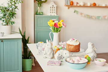 Easter sweet bread, Easter cake and multi-colored eggs with tulips and a white rabbit. Holidays breakfast concept with copy space. Retro style in tones. Easter greeting card template