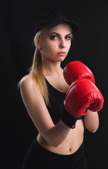 Beautiful young girl learns self-defense techniques in red Boxing gloves, black top and shorts