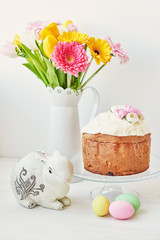 Easter cake, eggs and rabbits with fresh flowers on the table, the kitchen is decorated for Easter