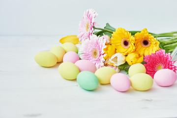 Obraz na płótnie Canvas Spring and Easter holiday concept with copy space. Template Easter Greeting Card. Easter eggs and flowers on white background. aster decoration with eggs.