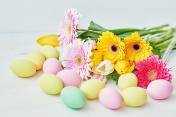 Obraz na płótnie Canvas Spring and Easter holiday concept with copy space. Template Easter Greeting Card. Easter eggs and flowers on white background. aster decoration with eggs.