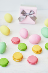 Spring and Easter holiday concept with copy space. Template Easter Greeting Card. Easter decoration with eggs and gift box. Macarons with Easter eggs background