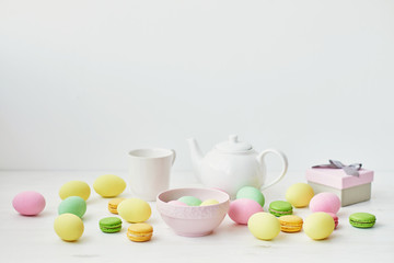 Spring and Easter holiday concept with copy space. Template Easter Greeting Card. Easter decoration with eggs and gift box. Macarons with Easter eggs background
