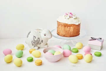 Easter sweet bread, Easter cake and multi-colored eggs with tulips and a white rabbit. Holidays breakfast concept with copy space. Retro style in tones. Easter greeting card template