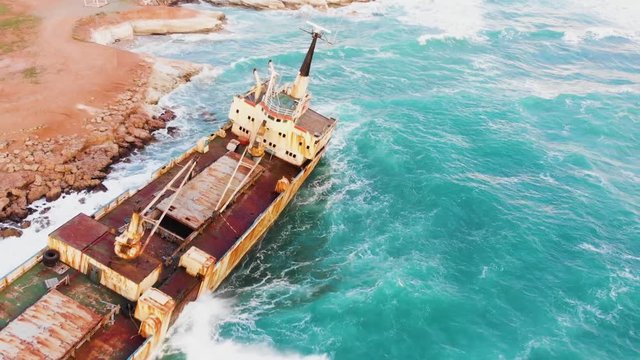 Beautiful shipwreck aerial footage. Drone footage of a shipwreck near Paphos, Cyprus on the sunset. Mediterranean sea shore on the sunset. Stormy sea, Cyprus.