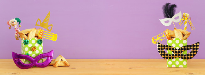 Purim celebration concept (jewish carnival holiday) over wooden table and pink background.