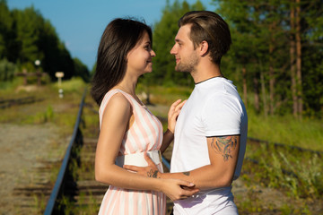 Obraz premium loving couple walking along train rails on a sunny day
