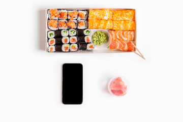 sushi set rolls on white background chopsticks wasabi ginger phone delivery food