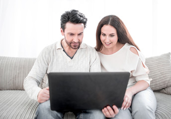 laughing couple looking at the laptop screen.