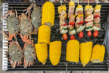seafood, corn and bbq grilling on steel tray at the beach.