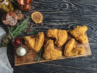 fried chicken wings in batter, red and white sauce on a dark surface