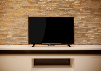 TV on a white shelf, stone wall
