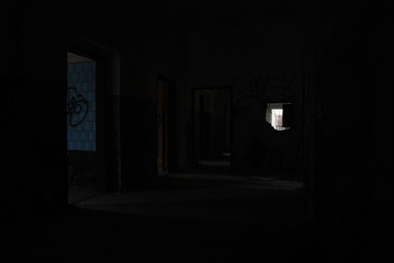 Dark corridor of abandoned decay building with light shining from rooms, urbex 