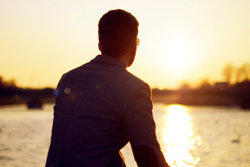 Silhouette of a man . sunset lake and river nature background beautiful sky. Businessman looks into...