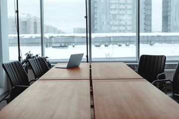 Large bright office in a loft style, with windows, concrete walls and a laptop on a wooden table