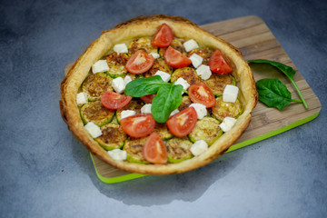 Homemade tart with grilled zucchini, tomatoes, goat's cheese and spinach