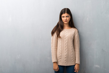 Teenager girl with sweater on a vintage wall feeling upset