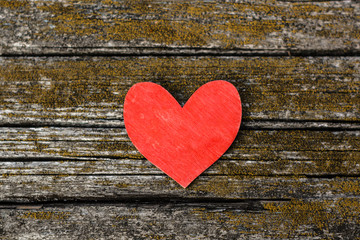 Red wooden heart on an old weathered wooden surface with cracks background