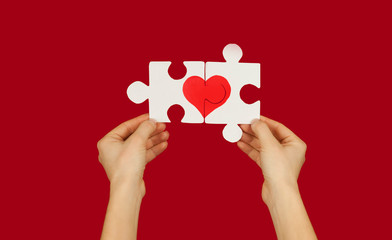 Puzzle with a red heart in the hands of a loving couple. Valentine's day concept.On a isolated background