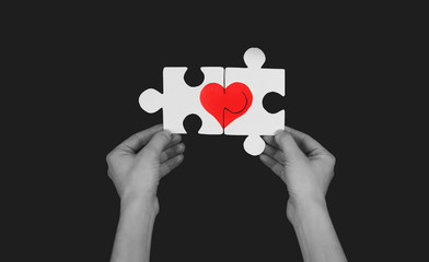Puzzle with a red heart in the hands of a loving couple. Valentine's day concept.On isolated background