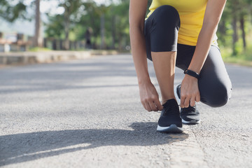 A young woman stopped to tie a string while running in the stadium, Fitness woman runner tying shoelace before running 