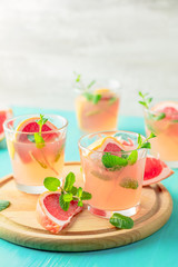 Pink alcoholic cocktail with grapefruit, ice and min