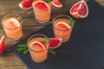 Pink cocktail with grapefruit, ice and rosemary