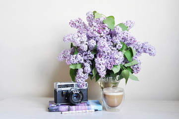 bouquet of flowers in a vase, cup of coffee and an old camera