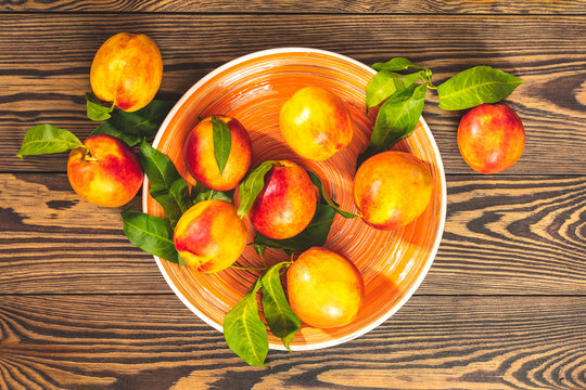 Peaches in orange plate on dark wooden background