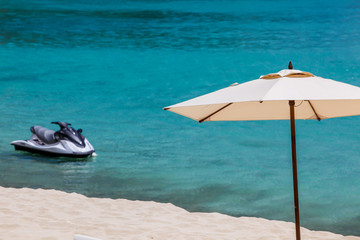 Umbrella with jet ski, beach sand and ocean