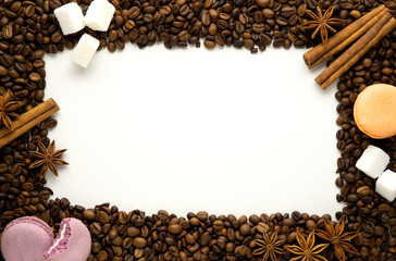 Creative concept photo of frame made of coffee beans with macaroons sugar cinnamon on white background.