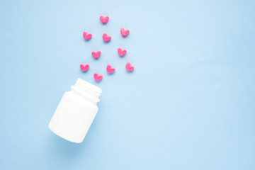 Creative concept valentine day photo of medical bottle with hearts on blue background.