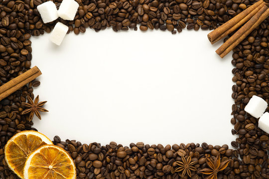 Creative concept photo of frame made of coffee beans with oranges sugar cinnamon on white background.