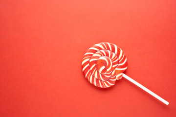 Creative concept photo of lolli pop popsicle candy on red background.