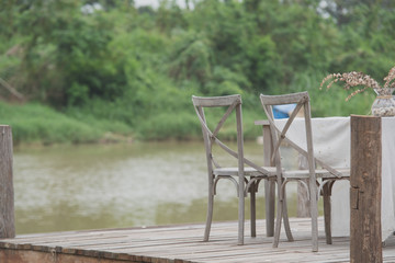 Wooden chairs on the bridge by the river,Desk and chair on the long wooden bridge near the river.