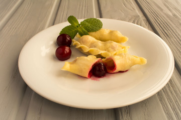 Dumplings with cherry in the white plate on the grey wooden  background