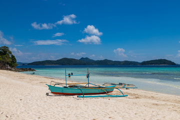 Tropical background view from Malcapuya island with traditional philippines boat and white sand beach. Travel vacation at Philippines.