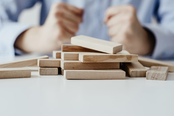 Scattered wooden blocks on the table in the background sitting man dressed in a business shirt. Concept of disorder, lack of order. Problems with the organization of time and work.