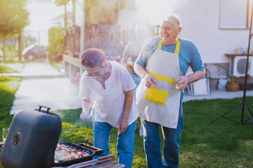 Father and son time. Happy father an son making barbeque in backyard. Drinking beer and having fun.