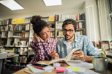 Female student listening while her friend explaining how to solve a problem.